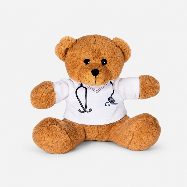 Teddy bear plush wearing a custom Harmony Healthcare shirt with stethoscope graphic and embroidered logo.