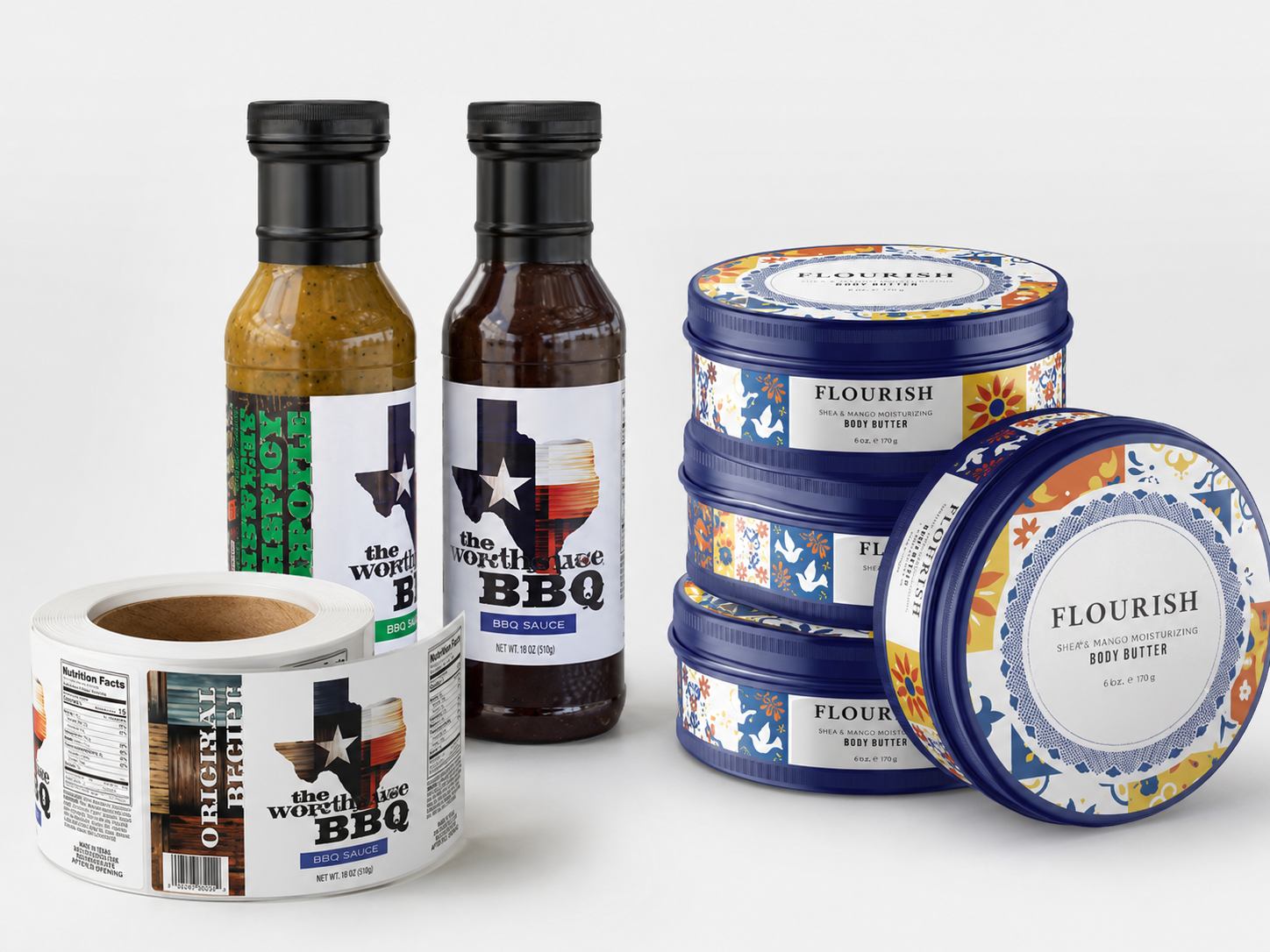 Custom product labels on BBQ sauce bottles, label rolls, and body butter containers displayed on a light gray background as examples of product label printing in Boise.