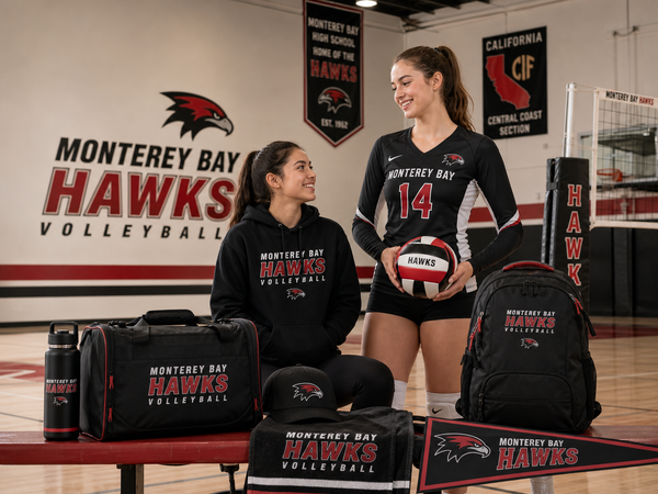 Two volleyball players with custom Monterey Bay Hawks uniforms, hoodie, backpack, duffel bag, hat, towel, water bottle, and pennant in a school gym.