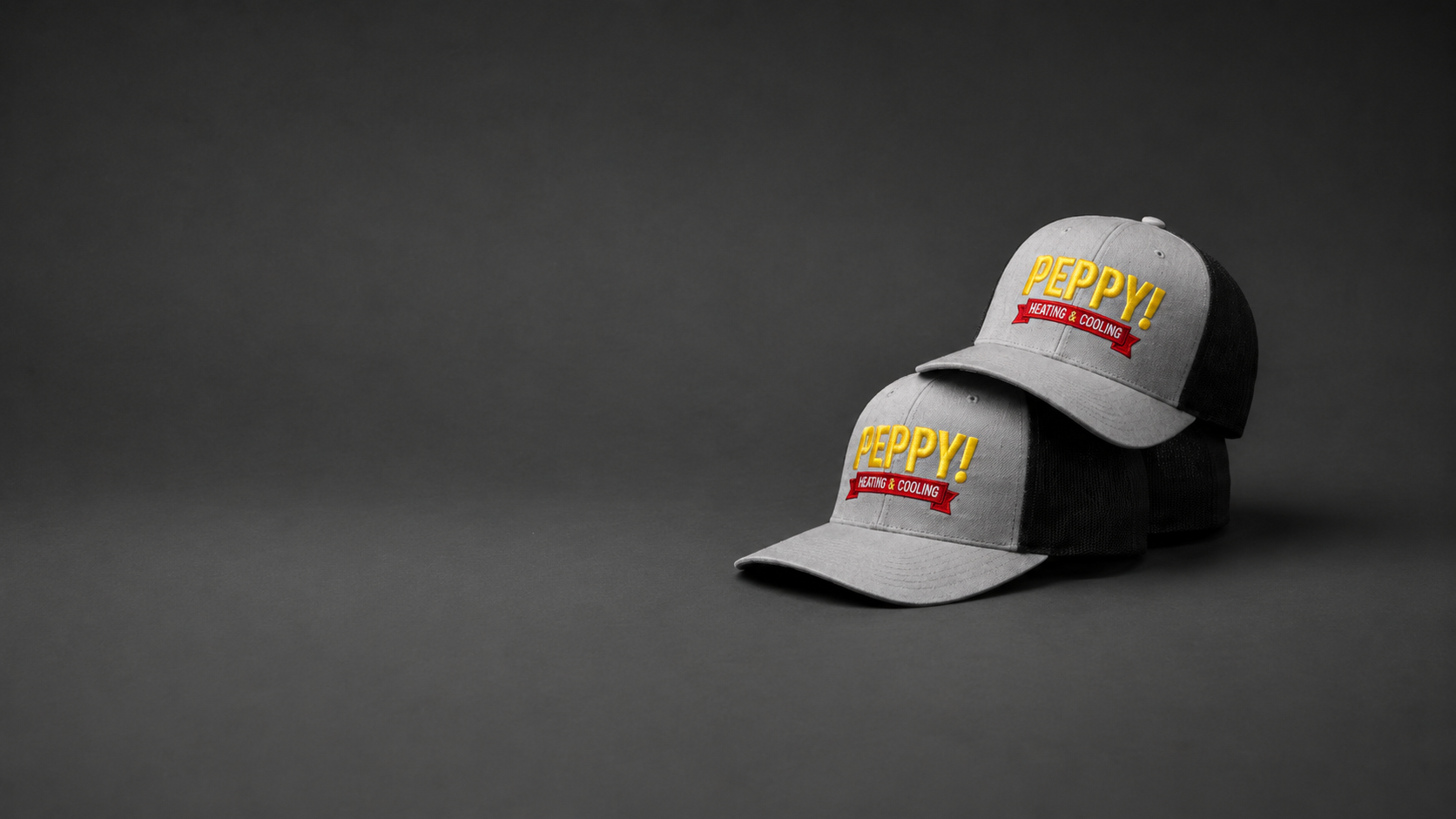 Custom embroidered trucker hats for Peppy Heating & Cooling, a Boise, Idaho company, featuring gray and black caps with yellow and red logo stitching by Brand Bros Boise.
